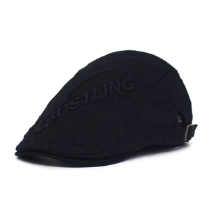 Detailed close-up of BUSTLING letter embroidery and quilted patterns on black cotton flat cap