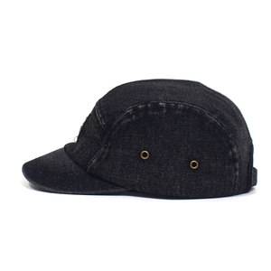 Detail view of black washed denim five-panel hat with bronze metal eyelets for ventilation