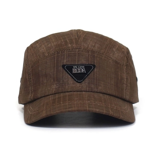 Detailed close-up of brown checked baseball cap with metallic triangle brand logo