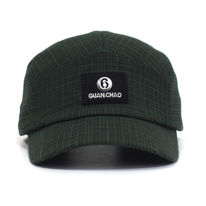 Detail van donkergroene 5-panel baseballpet met vierkante textuur en logo-patch