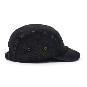 Detail view of black denim camper cap showing bronze eyelets and fine stitching