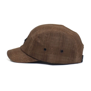 Detail view of brown five-panel camp cap featuring metal eyelets and adjustable strap