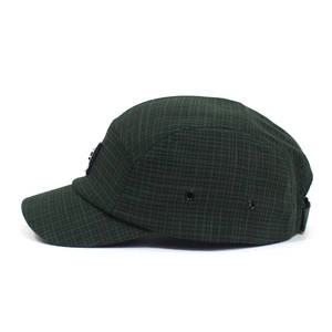 Detail van groene geruite five-panel camper hat met metalen ogen en verstelbare riem