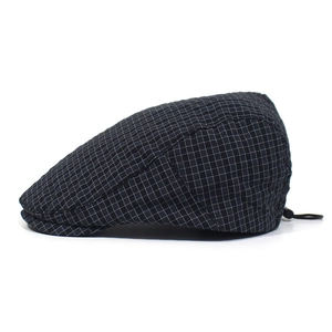 Detail of adjustable toggle on black plaid flat cap showing lightweight fabric texture