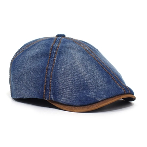 Detail of blue denim octagonal cap with contrast orange stitching and brown leather visor