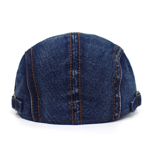 Detail view of washed denim flat cap showing metal buckles and contrast stitching
