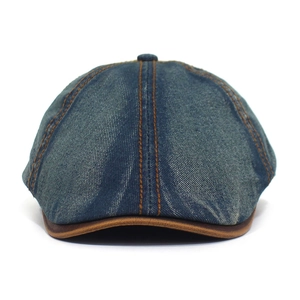 Detailed view of blue denim newsboy hat with orange stitching and leather trimmed brim