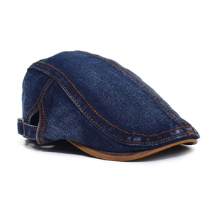 Detail view of denim flat cap with brown leather brim and contrast orange stitching