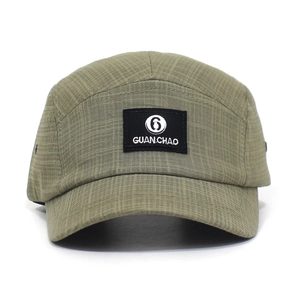 Detail van de kaki geruite 5-panel pet met zwarte GUAN CHAO merklogo patch erop