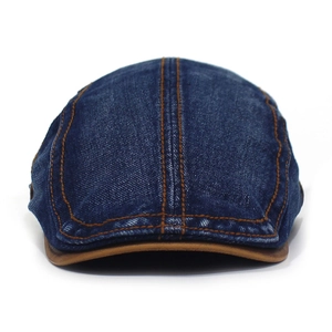 Detailed close-up of vintage denim flat cap with contrast stitching and leather brim edge