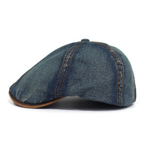Detail view of washed denim newsboy cap with orange stitching and faux leather brim piping
