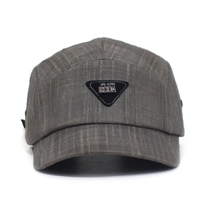 Close-up of gray checkered fabric and metal letter triangular badge on baseball cap