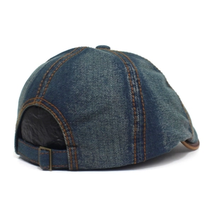 Detail of adjustable metal strap and orange stitching on washed blue denim flat cap