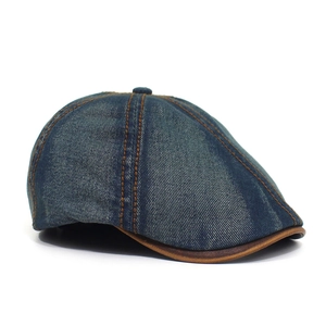 Macro detail of blue washed denim newsboy cap with brown contrast stitching and leather trim