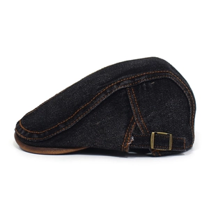 Detail of vintage denim flat cap featuring contrast stitching and leather brim