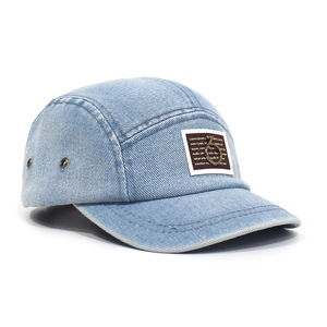 Detailed side view of washed light blue denim camper cap with metal eyelets and patch