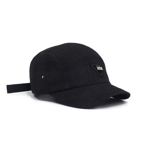 Close-up of black camper hat featuring a triangular metal logo with BEDA engraving