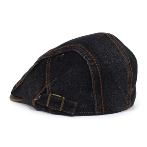 Detail of dark denim flat cap showing orange stitching and bronze adjustable metal buckle