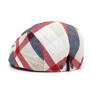 Detailed view of British style red blue and white plaid fabric on flat cap with metal buckle