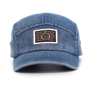 Close-up of washed denim baseball cap featuring a brown fabric patch and metal ring