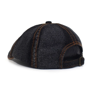 Detail of adjustable vintage bronze buckle and orange stitching on washed denim octagonal hat