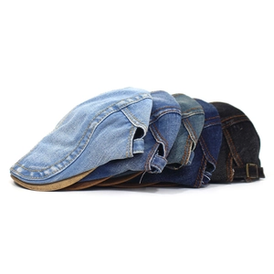 Detail of four denim ivy caps in varied washes featuring classic orange stitching