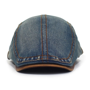 Detail of blue washed denim flat cap with contrast orange stitching and brown leather trim