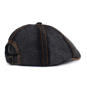 Detail of denim flat cap showing orange stitching and adjustable metal buckle back strap