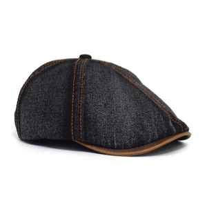 Detailed view of washed denim newsboy cap with orange stitching and leather trim