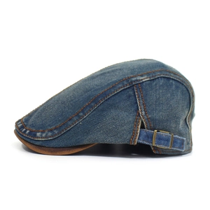 Close-up of vintage denim ivy cap with brown leather trim and copper side adjustment buckle