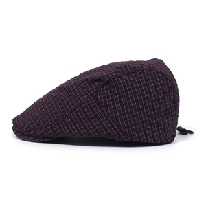 Detail of dark purple checkered flat cap with adjustable drawstring buckle on white background
