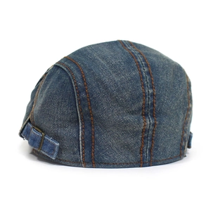Detail of blue denim beret featuring contrast brown stitching and adjustable metal buckle