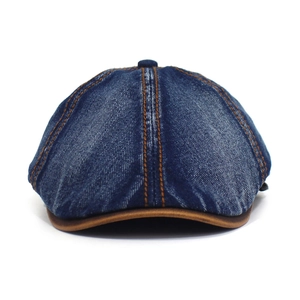 Macro detail of washed blue denim octagonal cap with brown leather brim and contrast stitching