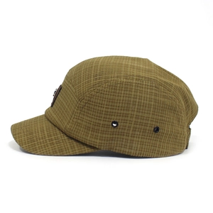 Detail van de bruin geruite five-panel pet met metalen oogjes en getextureerde stof