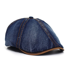 Close-up of vintage blue denim newsboy cap featuring brown stitching and leather brim