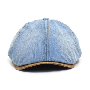 Detail of washed denim octagonal hat featuring contrast stitching and a brown suede brim