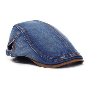 Detail of vintage denim flat cap featuring brown leather brim and contrast stitching