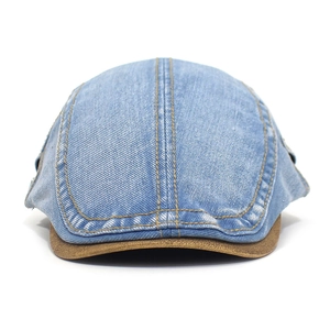 Detail view of washed denim ivy cap featuring contrast brown leather brim and yellow stitching