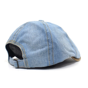 Detail of light blue washed denim octagonal cap with yellow stitching and metal buckle