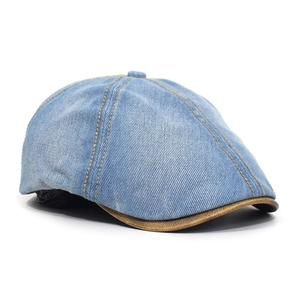 Detail of washed denim octagonal cap with yellow stitching and brown leather brim edge