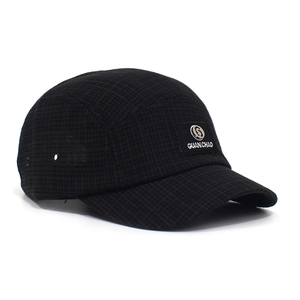 Detail van zwarte ruitvormige 5-panel baseballpet met metalen logo en stoftextuur