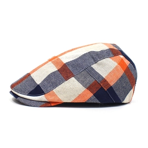 Detail of colorful plaid flat cap showing orange and navy cotton fabric texture and stitching