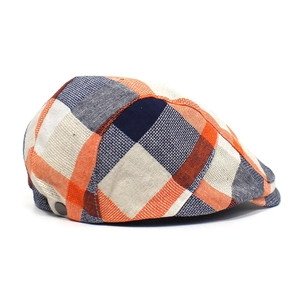 Detail of colorful plaid flat cap with metal button and breathable textured fabric