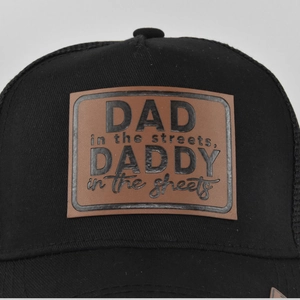 Close-up of brown leather patch with DAD text on black mesh trucker baseball cap