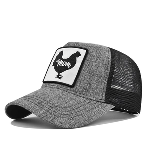 Detail van grijze mesh trucker pet met een haan patch en artistieke Mom tekst