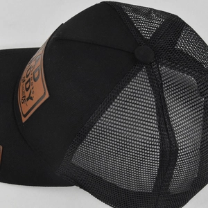 Detail of black trucker hat mesh material and brown leather patch with embroidery