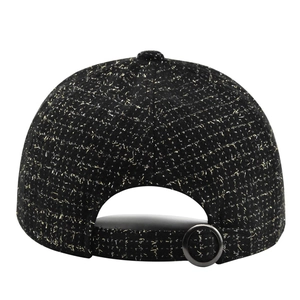 Détail de la casquette en tweed noir avec fils dorés et boucle en métal réglable