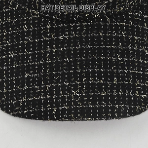 Vue macro d'un tricot noir avec motif en croix de lurex doré et finition métallique