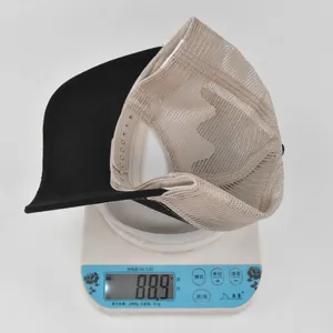 Detailed view of black mesh trucker hat showing a weight of 88.9g on a digital scale