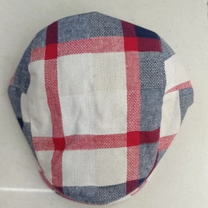 Close-up of red and blue plaid fabric texture and stitching on the British style flat cap